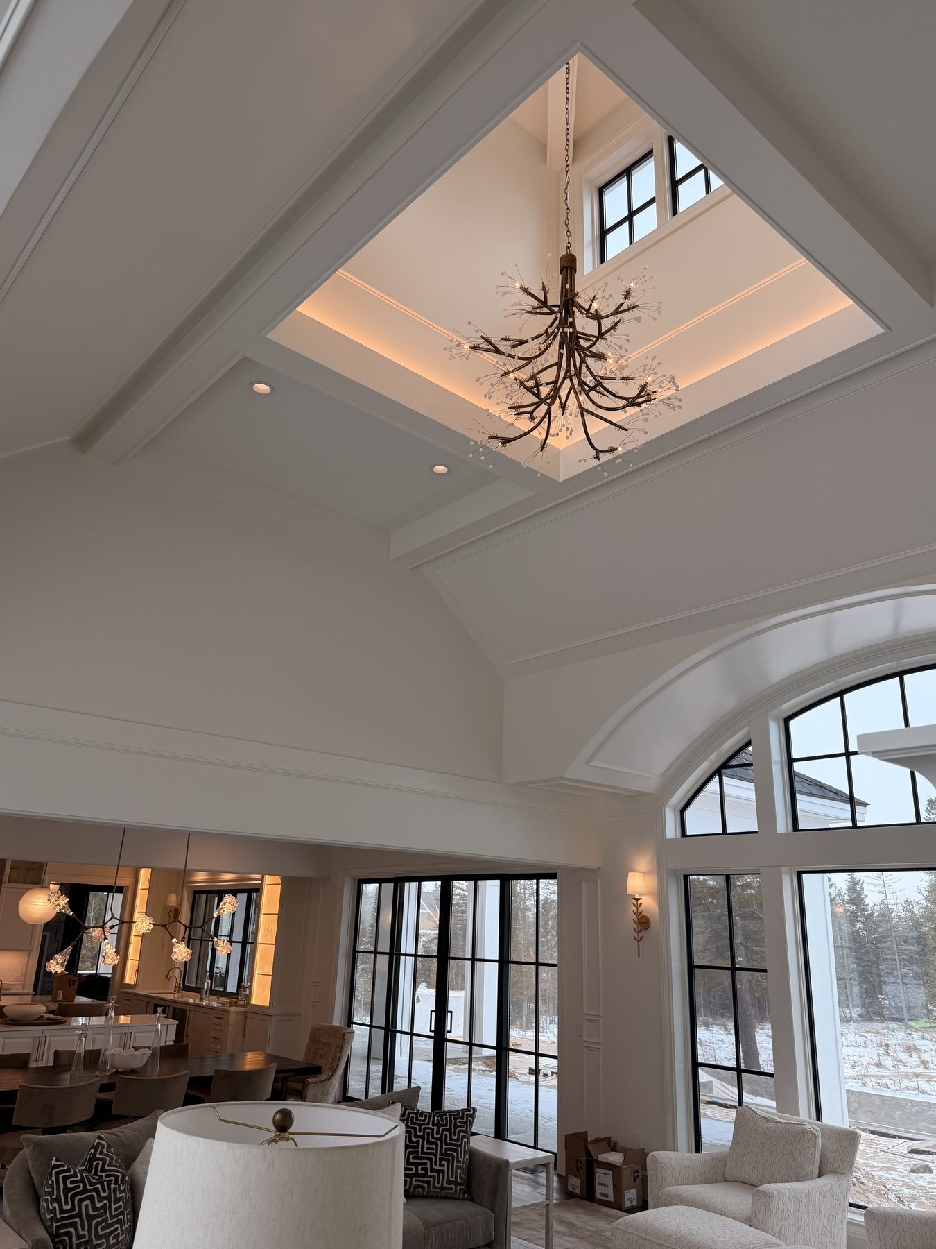 Branch-style metal and crystal chandelier in a tall white great room with arched windows